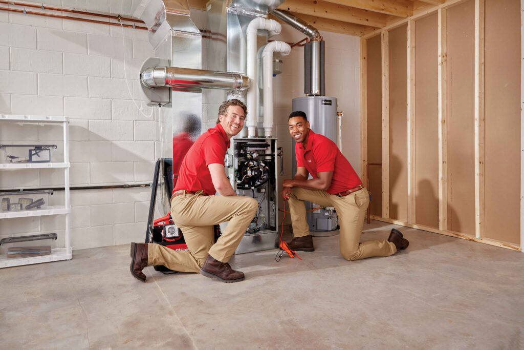 Two technicians repairing a furnace