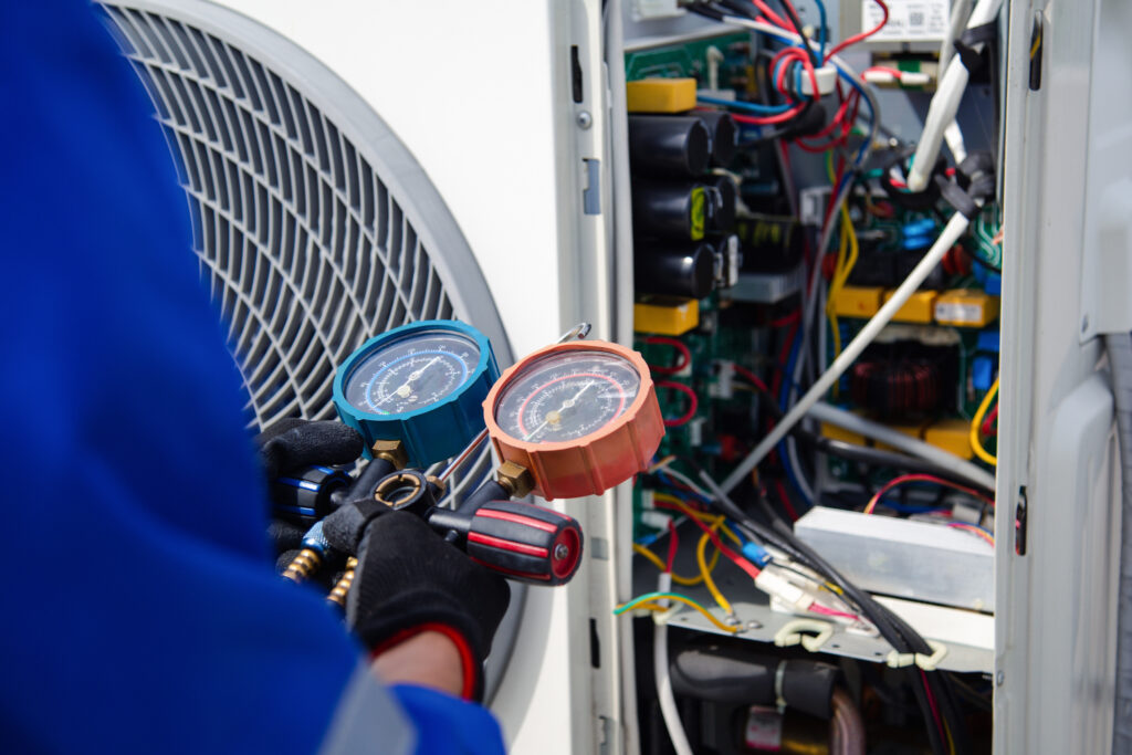 air conditioner technician is using a gauge to measure the refrigerant pressure